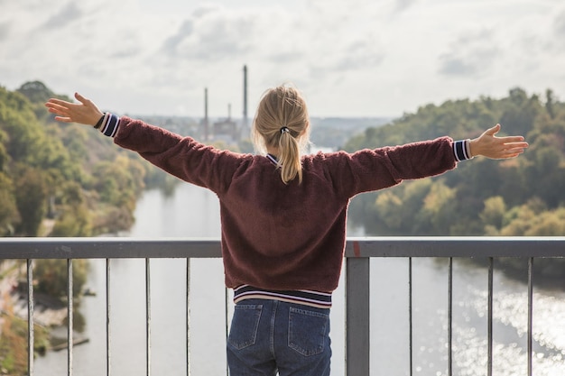 Fille heureuse sur le pont et se sentir libre et regarder la rivière bleue