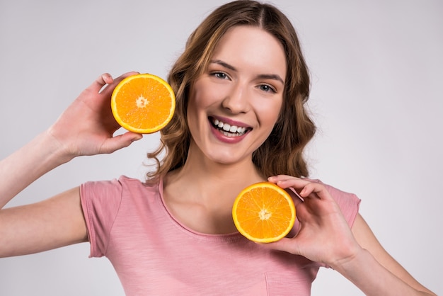 Fille heureuse posant avec orange souriant isolé.