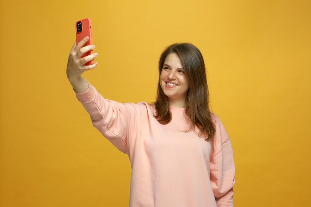 Fille heureuse prenant selfie tenant un téléphone en regardant un smartphone à l'aide d'un appareil photo mobile souriant s'amusant