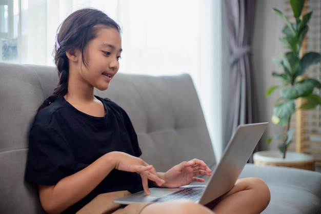 Une fille heureuse qui apprend l'anglais en ligne avec un ordinateur portable à la maison