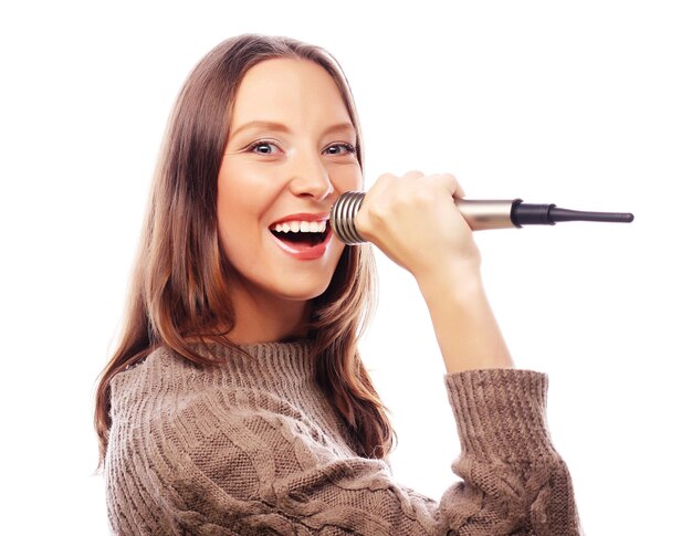 Une fille heureuse qui chante Une femme belle avec un micro sur un fond blanc