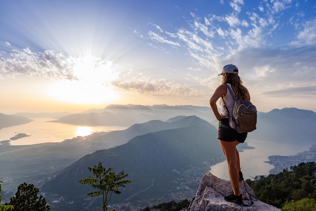 Une fille heureuse avec un sac à dos est au bord d'une haute montagne au monténégro