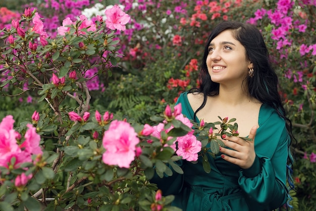 Fille heureuse souriante dans le jardin fleuri, beau jardin de fleurs roses. Photo de haute qualité