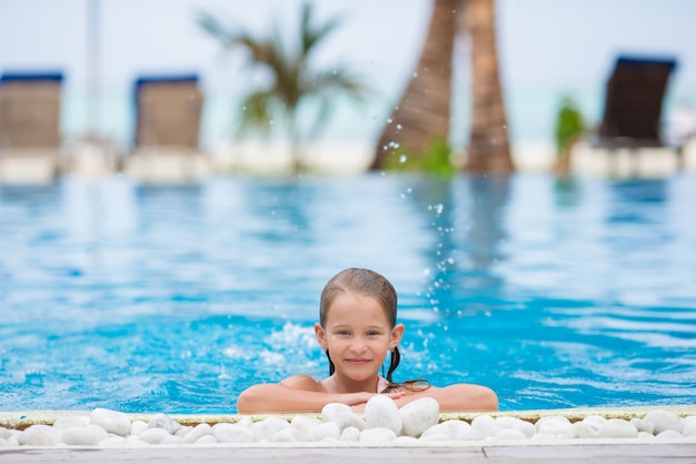 Fille heureuse souriante dans la piscine extérieure