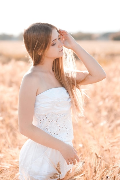 Fille heureuse souriante dans la prairie de seigle à l'extérieur