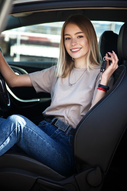 Fille heureuse de sourire dans une nouvelle voiture avec des clés dans sa main Mode de vie