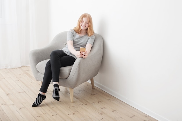 Fille heureuse avec téléphone en fauteuil