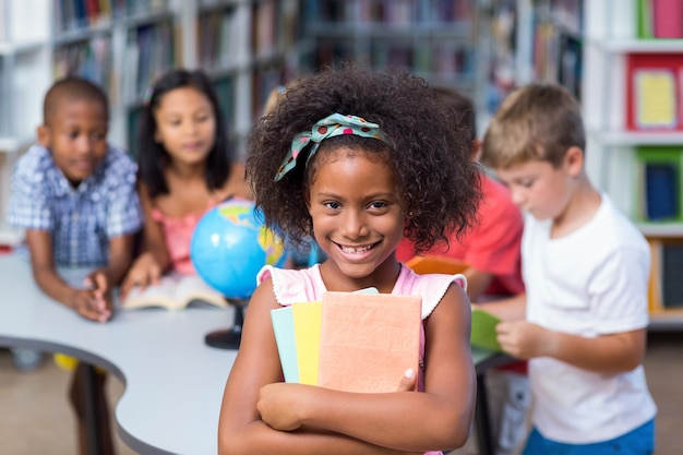 Fille heureuse, tenue de livres contre ses camarades de classe