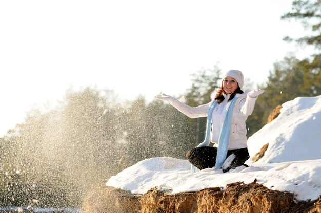 Photo fille heureuse en vêtements d'hiver blancs avec les yeux fermés jette de la neige