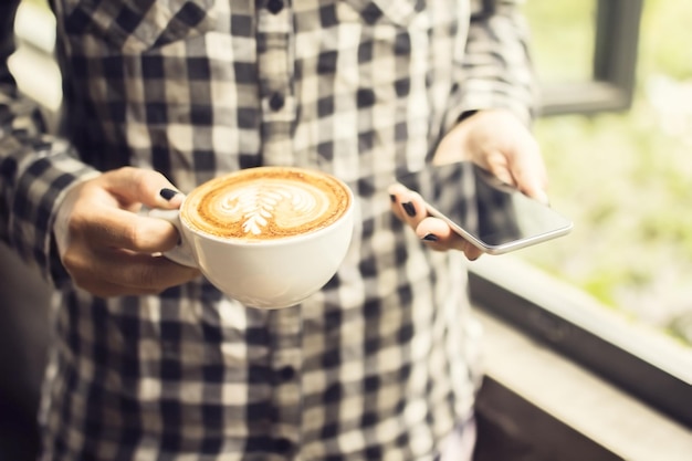 Fille hipster avec cappuccino et smartphone