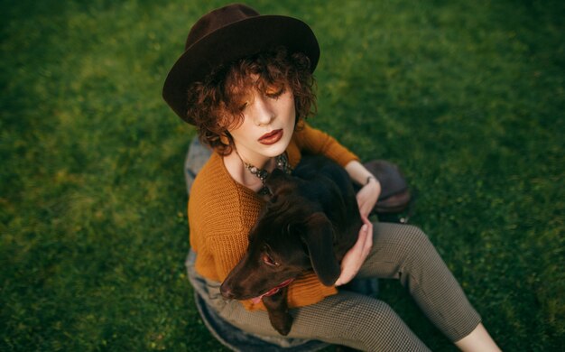 Fille de hipster étreignant un beau chien brun sur fond d'herbe verte