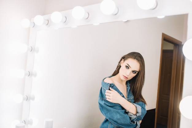 Fille de hipster regardant miroir, yeux enfumés, teint parfait