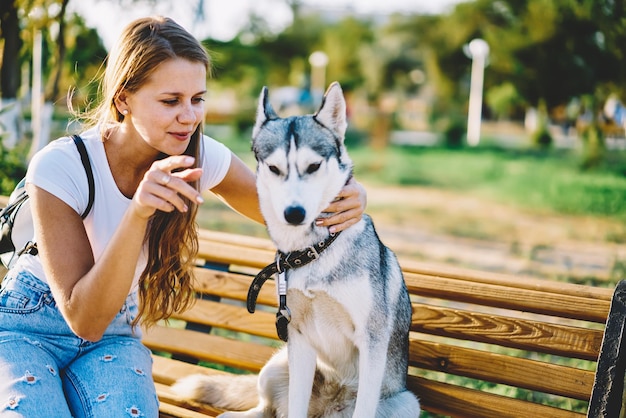 fille hipster s'amusant avec un toutou dans le parc jolie jeune femme avec un husky jouant sur un banc