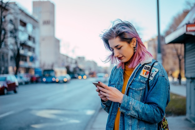 Fille de hipster en utilisant le téléphone à la rue.