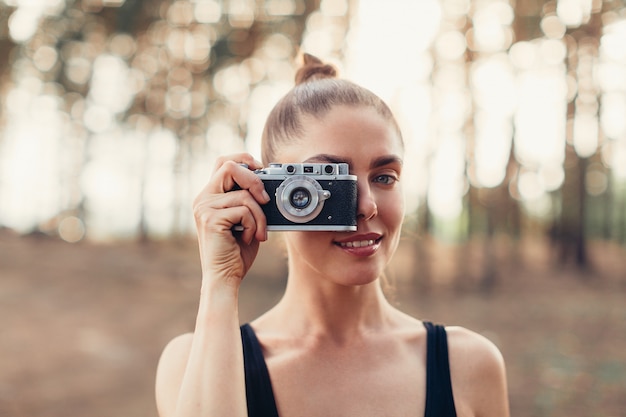 Fille de hipster avec utilisation d&#39;appareil photo vintage