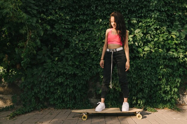 Fille hispanique athlétique en streetwear élégant se dresse sur un longboard