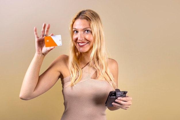 Une fille hispanique blonde détient une carte de crédit joyeuse et souriante expression heureuse