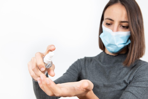 Fille hispanique se lavant les mains avec du gel désinfectant tout en portant un masque médical