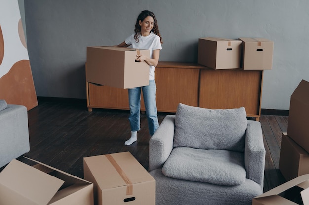 Une fille hispanique tient une boîte et quitte l'appartement Une jeune femme heureuse déménage seule