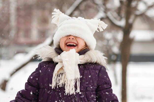 Fille d'hiver dans un parc enneigé Visage d'enfant souriant positif Hiver Vacances actives Enfant heureux