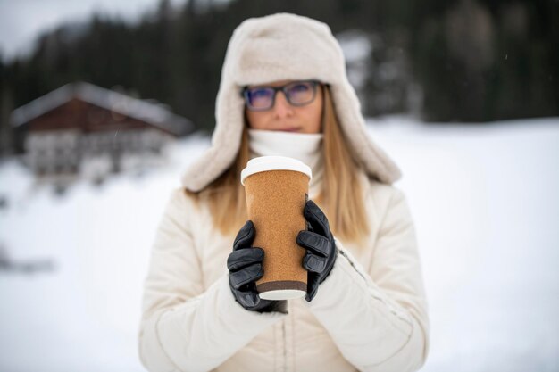 Fille en hiver dans des vêtements légers tenant une boisson brune thé au café en verre adapté au mocap