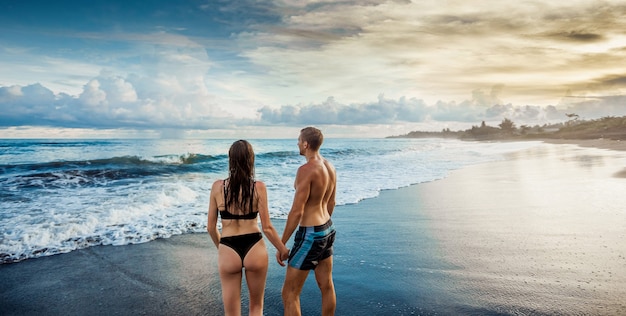 Fille et hommes se tiennent sur la plage et regardent le panorama de vue arrière de l'océan