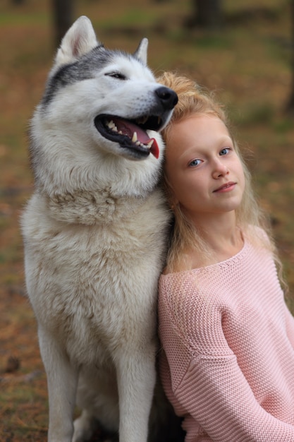 Une fille avec un husky se promène dans la forêt