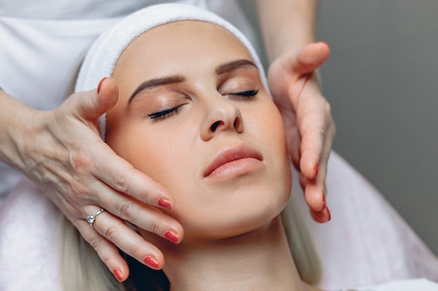 Fille idéale détendue bénéficiant d'un massage du visage dans un salon de beauté après avoir subi des procédures cosmétiques.