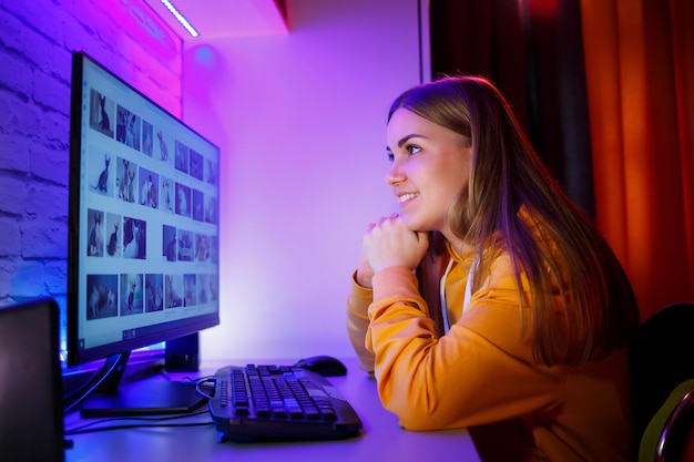 Une fille indépendante regarde sur un écran d'ordinateur un chat Assis dans un appartement à un bureau d'ordinateur