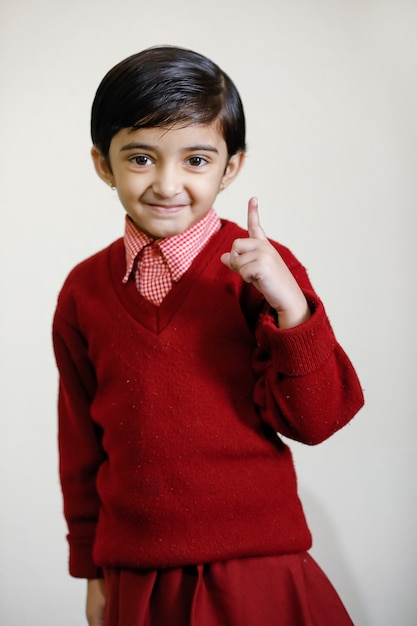 Fille indienne en uniforme scolaire et montrant le doigt