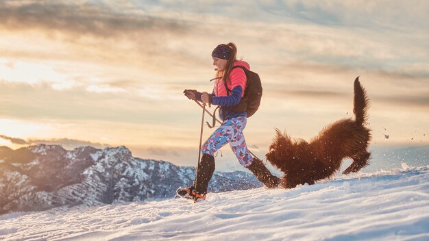 Fille inséparable et son chien jouent dans la neige lors d'une randonnée hivernale