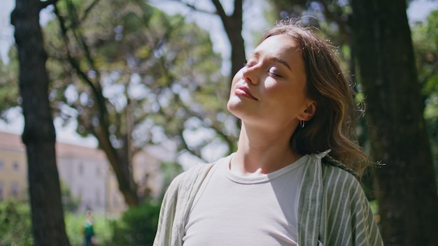 Une fille insouciante au soleil, fermant les yeux sur la nature, une belle femme en gros plan.