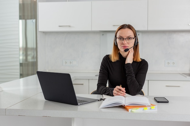 Photo une fille intelligente dans des lunettes et un casque est assise devant un ordinateur portable dans le bureau à domicile organise une formation en ligne photo de haute qualité