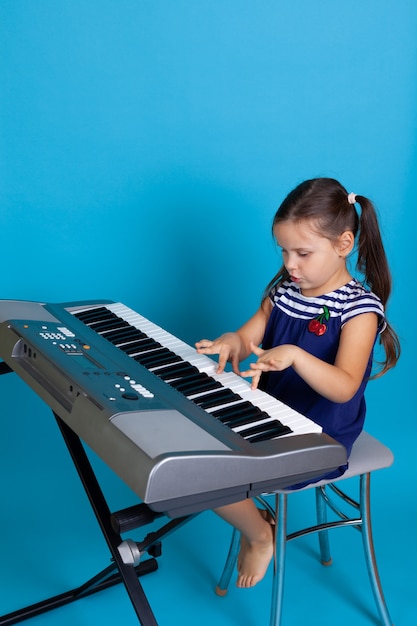 Fille intéressée jouant une mélodie sur les touches d'un synthétiseur électronique