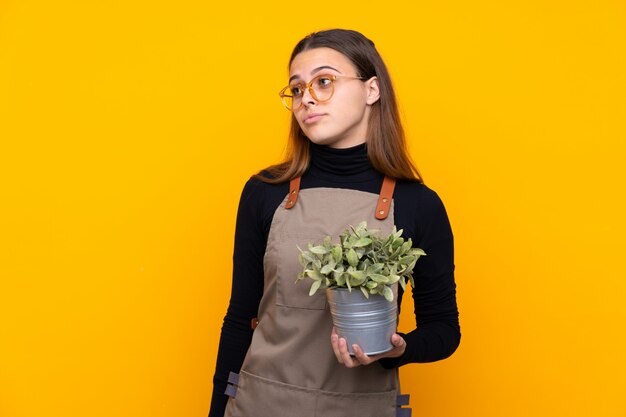 Fille de jardinier sur mur jaune isolé