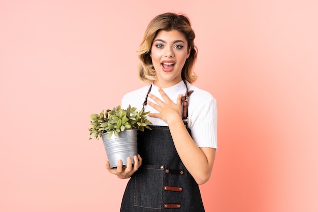 fille de jardinier tenant une plante avec une expression faciale surprise