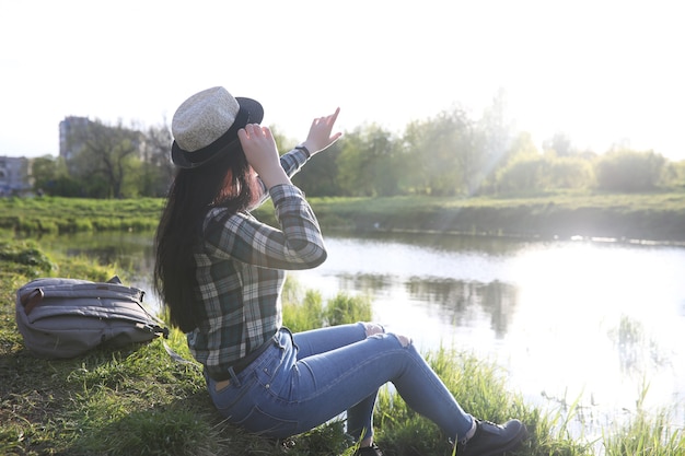 Une fille en jeans et chapeau parcourt l'été à la campagne