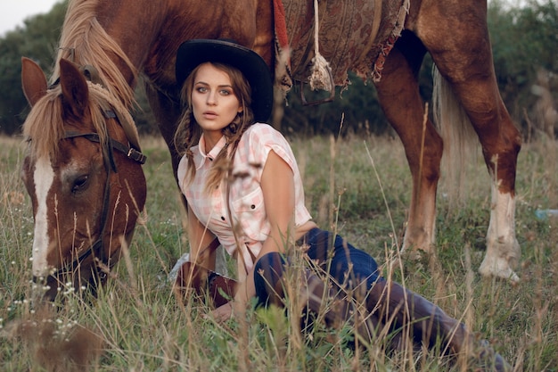 fille en jeans chemise chapeau noir cowboy avec cheval