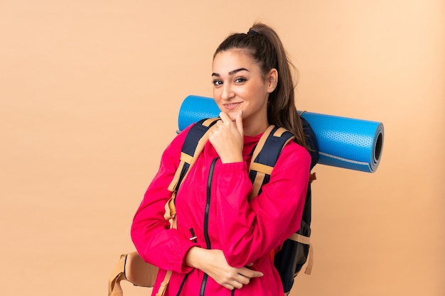 Fille de jeune alpiniste avec un gros routard isolé sur un mur beige en riant