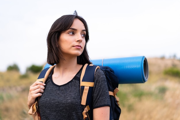 Fille jeune alpiniste avec un gros sac à dos à l'extérieur