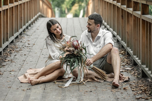 Une fille et un jeune homme sont assis sur le pont et apprécient la communication, un rendez-vous dans la nature, une histoire d'amour.