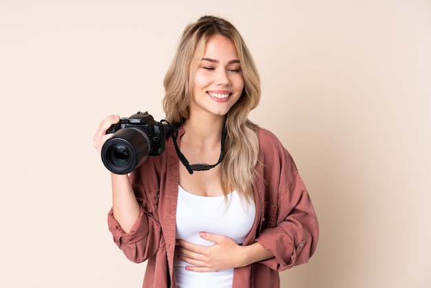 Fille jeune photographe sur mur isolé souriant beaucoup