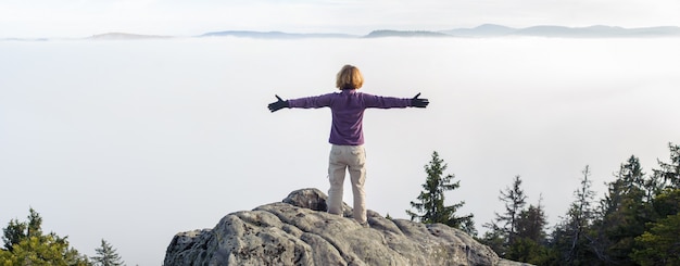 Fille de jeune touriste debout au sommet des rochers