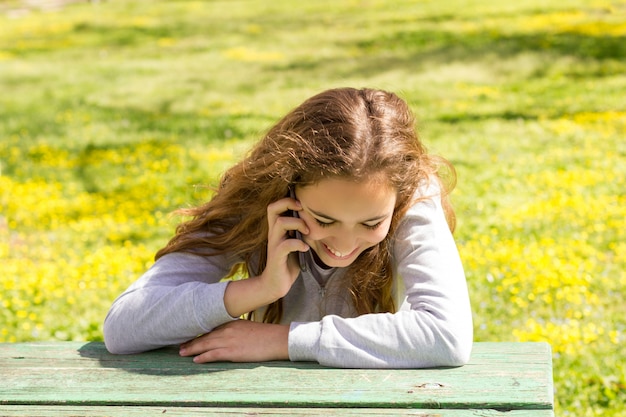 Fille jolie adolescente avec smartphone cellpfone mobile dans le parc de l'été