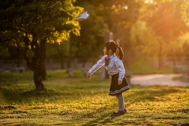 Une fille jouant avec un avion en papier dans le parc