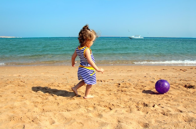 Fille jouant avec ballon sur la plage