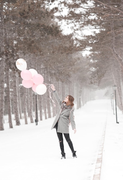 Fille jouant avec des ballons dans le parc sur la neige