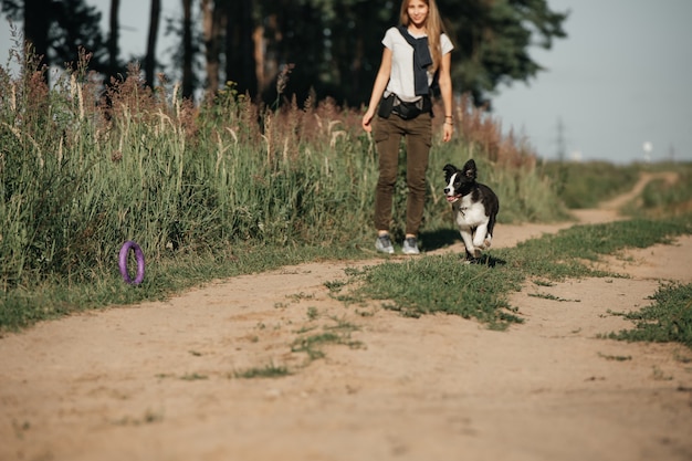 Fille jouant avec chiot border collie noir et blanc sur le chemin de la forêt