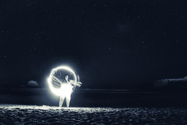 Photo une fille jouant dans la nuit faisant des cercles de lumière avec les étoiles qui brillent derrière