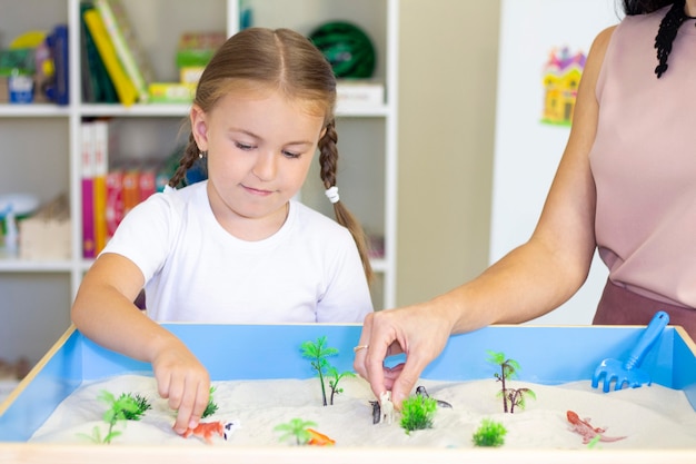 Fille jouant dans le sable, activité éducative avec un enfant